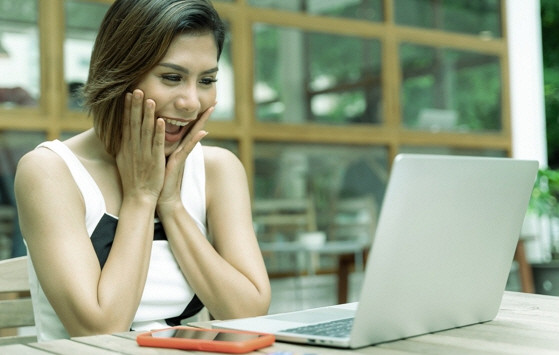 a happy woman in front of a laptop
